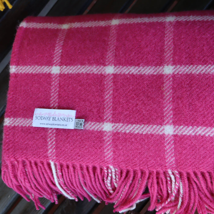 Pink plaid wool blanket with fringes and a visible Solway Blankets label folded neatly