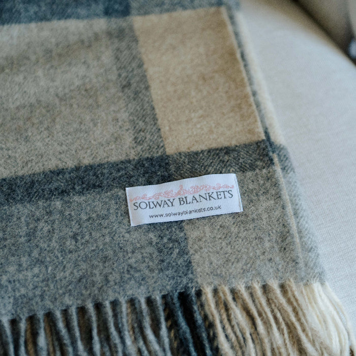 Close up, folded soft grey and white plaid blanket with a Solway Blankets label on a chair 