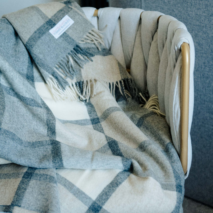 Soft grey and white plaid throw draped over a neutral colored chair 
