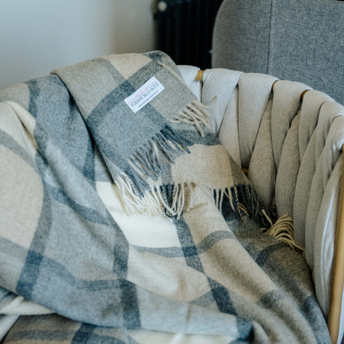 Soft grey and white plaid blanket draped over a neutral chair with a visible Solway Blankets label