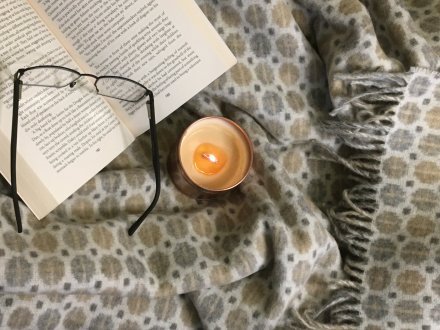 merino wool throw, book, reading glasses and scented candle