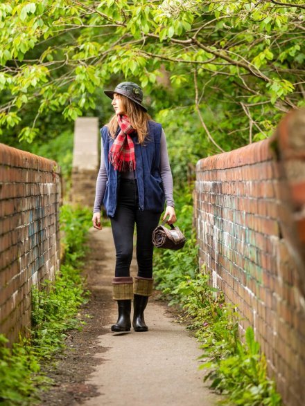 Lady with hat and scarf walking in countryside with picnic blanket roll